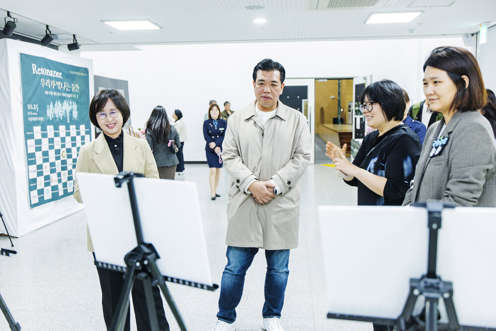 전시장 내부에서 여러 사람이 전시 작품을 보고 대화하는 모습