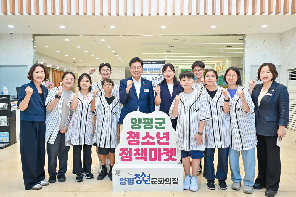 실내에서 청소년들이 줄무늬 유니폼을 입고 성인들과 함께 서서 손을 주먹 쥐고 포즈를 취하는 단체 사진